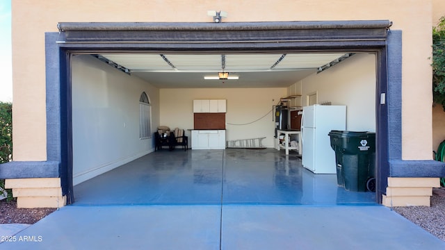 garage featuring a garage door opener, concrete driveway, and freestanding refrigerator