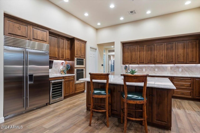 kitchen with a center island, beverage cooler, light hardwood / wood-style floors, and appliances with stainless steel finishes