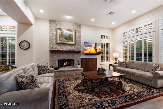 living room featuring a stone fireplace, ceiling fan, and hardwood / wood-style floors