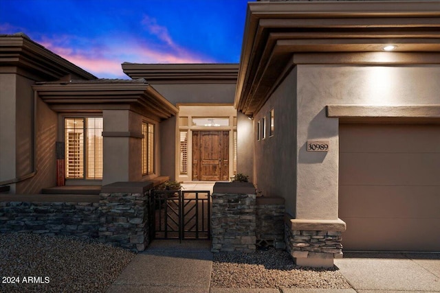 exterior entry at dusk featuring a garage