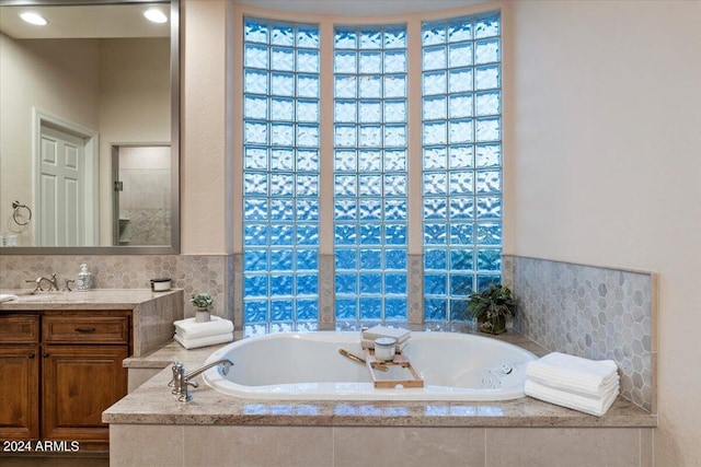 bathroom with vanity and tiled bath