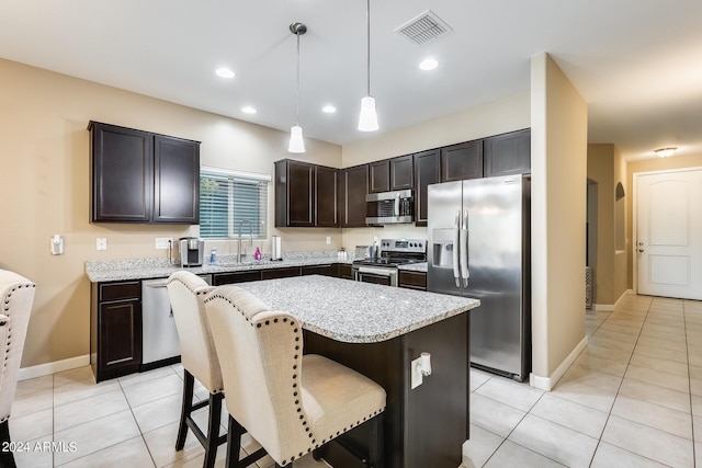 kitchen featuring sink, stainless steel appliances, a kitchen island, decorative light fixtures, and light tile patterned flooring