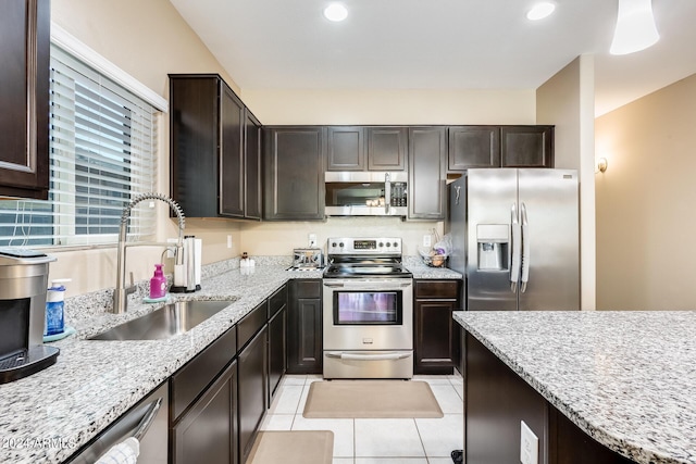 kitchen featuring sink, light stone countertops, dark brown cabinets, light tile patterned flooring, and stainless steel appliances