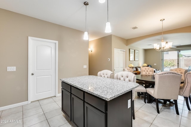 kitchen featuring light stone counters, light tile patterned floors, decorative light fixtures, a chandelier, and a kitchen island