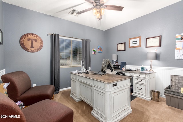 carpeted home office with ceiling fan and wood walls