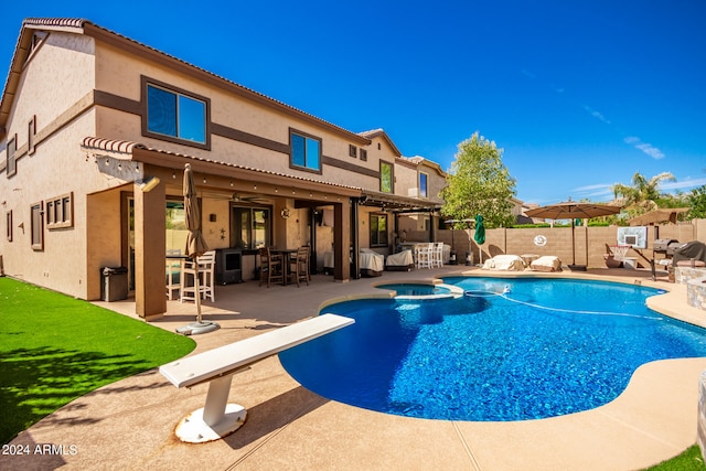 view of swimming pool featuring a diving board, an outdoor bar, an in ground hot tub, and a patio