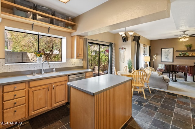 kitchen featuring ceiling fan with notable chandelier, sink, tasteful backsplash, and a kitchen island