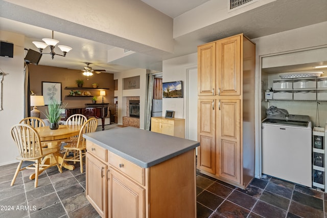 kitchen with ceiling fan, light brown cabinets, a kitchen island, and washer / dryer