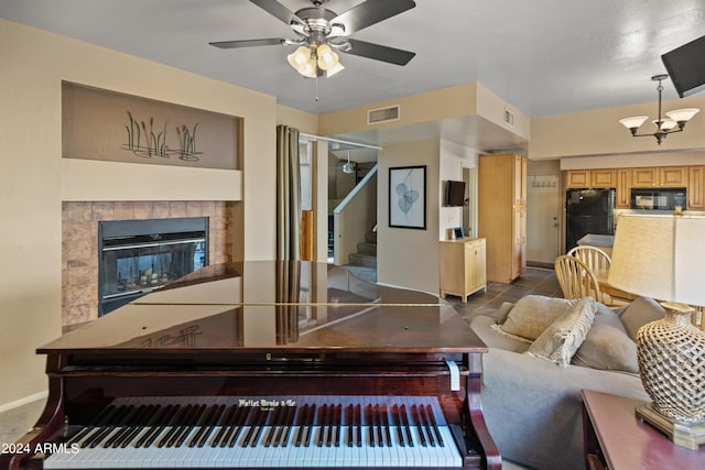 living room with a tile fireplace, ceiling fan, and dark tile patterned floors