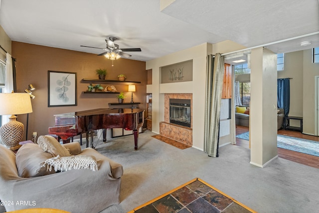 carpeted living room with a tile fireplace and ceiling fan