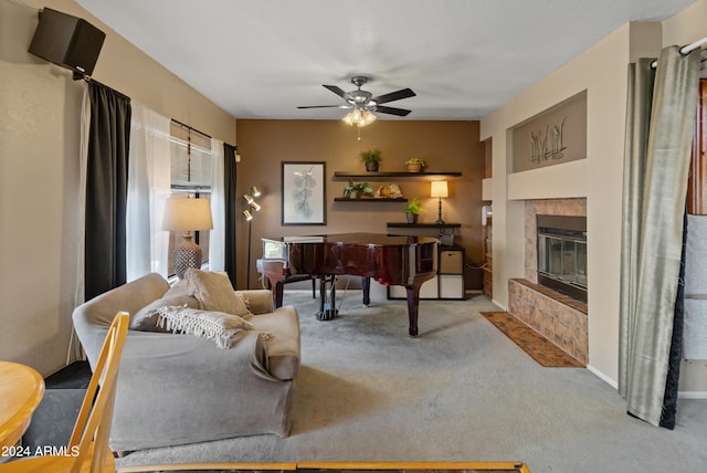 living room with a tiled fireplace, ceiling fan, and light colored carpet