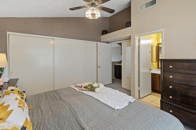 bedroom with high vaulted ceiling, light tile patterned floors, a closet, ceiling fan, and ensuite bath