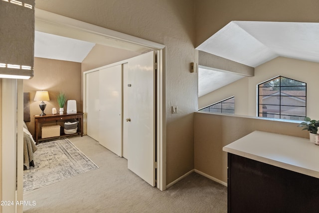 hallway featuring lofted ceiling and light colored carpet