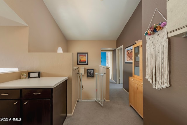 kitchen featuring dark brown cabinetry, lofted ceiling, and light carpet