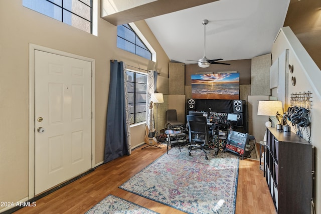 office with light hardwood / wood-style floors, ceiling fan, and high vaulted ceiling