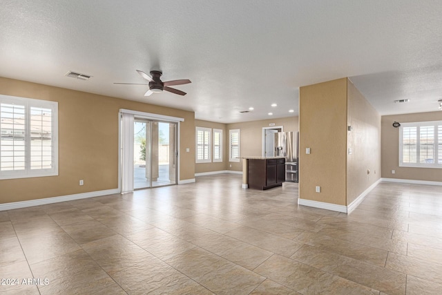 unfurnished living room with ceiling fan and a textured ceiling