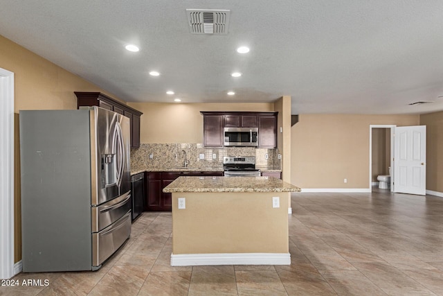 kitchen featuring sink, a center island, light stone counters, backsplash, and appliances with stainless steel finishes