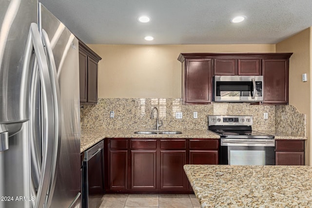 kitchen with tasteful backsplash, light stone countertops, sink, and appliances with stainless steel finishes