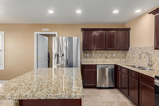 kitchen with light stone counters, sink, a center island, and appliances with stainless steel finishes