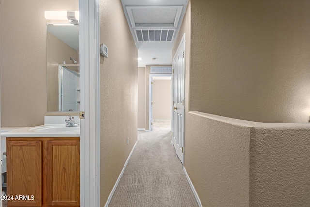 corridor featuring light carpet and sink