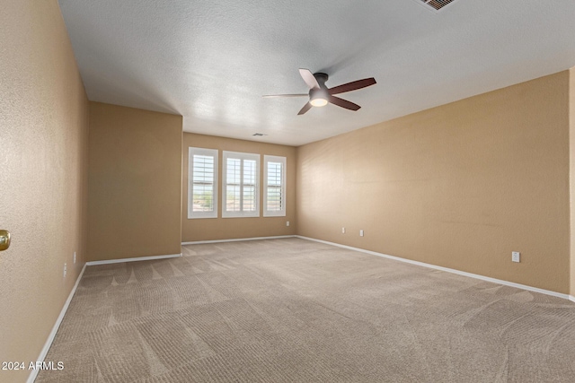 empty room with a textured ceiling, light colored carpet, and ceiling fan