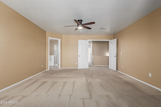 unfurnished bedroom with light carpet, a textured ceiling, and ceiling fan