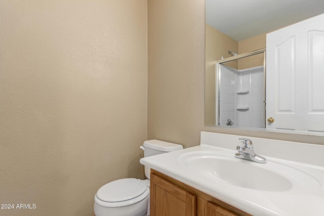 bathroom with vanity, toilet, a shower, and a textured ceiling