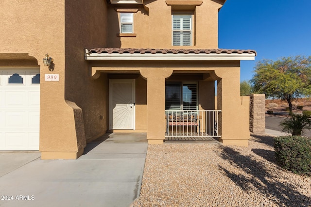 doorway to property featuring covered porch and a garage