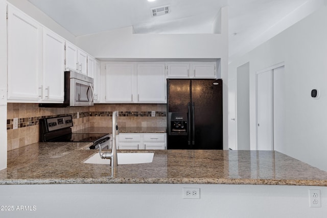 kitchen with visible vents, light stone counters, a peninsula, stainless steel appliances, and backsplash