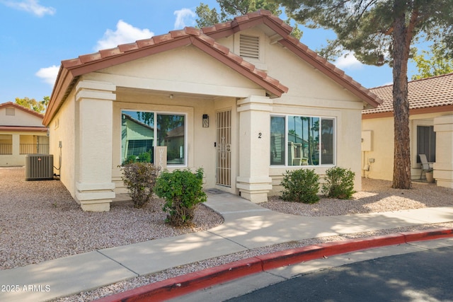 view of front of home with central air condition unit, a tiled roof, and stucco siding