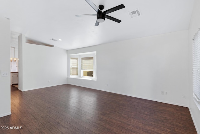 spare room featuring dark wood-style flooring, visible vents, baseboards, and ceiling fan with notable chandelier