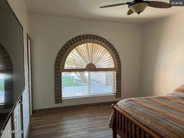 bedroom with wood finished floors, a ceiling fan, and baseboards