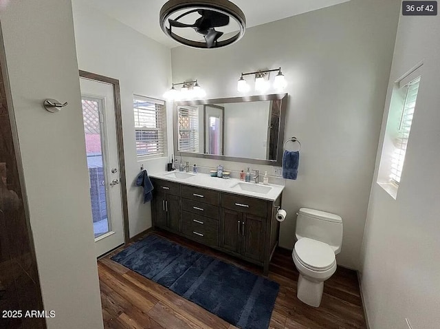 full bath featuring double vanity, wood finished floors, a sink, and toilet