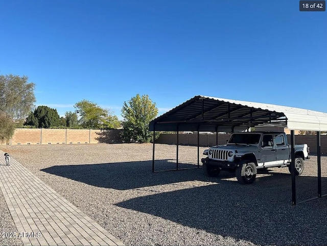 view of parking / parking lot with a carport and fence