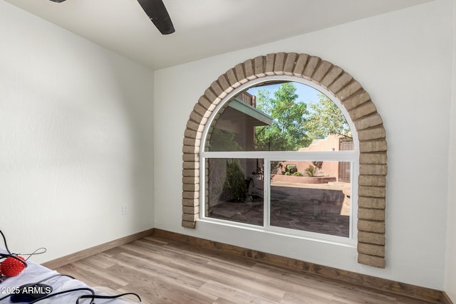 empty room with ceiling fan, wood finished floors, and baseboards