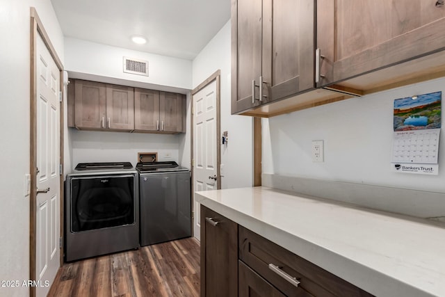 laundry area featuring dark wood-style floors, cabinet space, visible vents, and separate washer and dryer