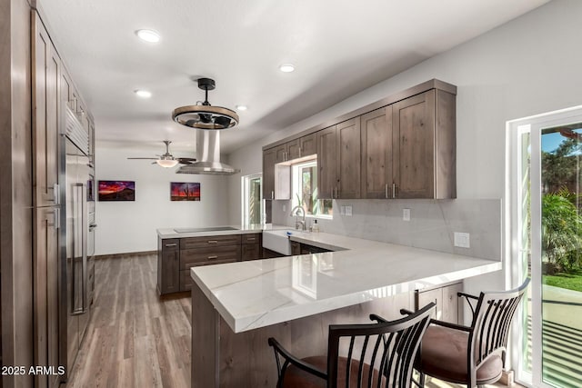 kitchen featuring a peninsula, a wealth of natural light, black electric cooktop, and backsplash