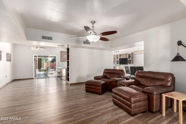 living area with ceiling fan, visible vents, and wood finished floors