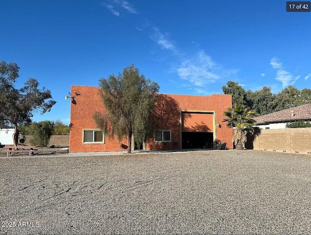 view of front of home featuring a garage, fence, and stucco siding