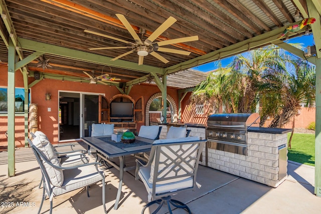 view of patio / terrace with area for grilling, ceiling fan, fence, outdoor dining area, and exterior kitchen