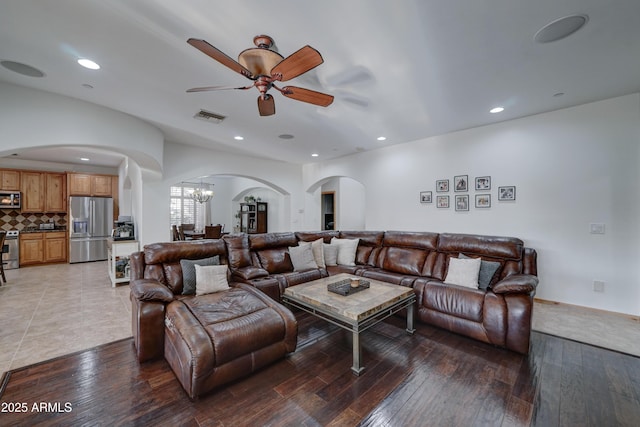 living room with dark wood-type flooring and ceiling fan with notable chandelier