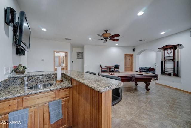 kitchen featuring light tile patterned flooring, sink, pool table, ceiling fan, and light stone countertops