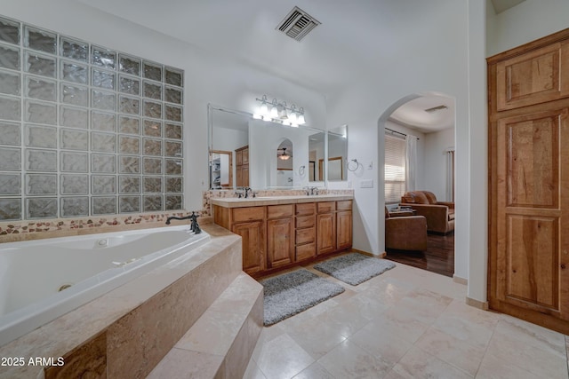 bathroom featuring tile patterned flooring, vanity, and tiled tub