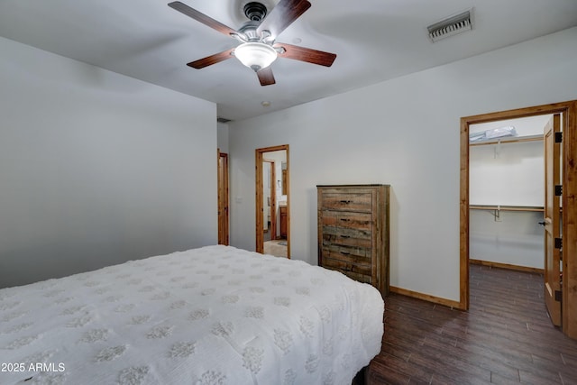 bedroom with ceiling fan, a walk in closet, dark hardwood / wood-style flooring, and a closet