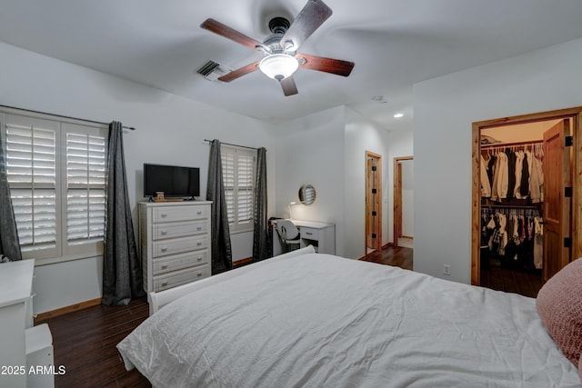 bedroom with ceiling fan, dark hardwood / wood-style floors, a closet, and a spacious closet