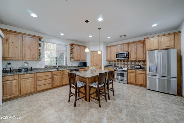 kitchen with pendant lighting, a kitchen breakfast bar, stainless steel appliances, a kitchen island, and dark stone counters