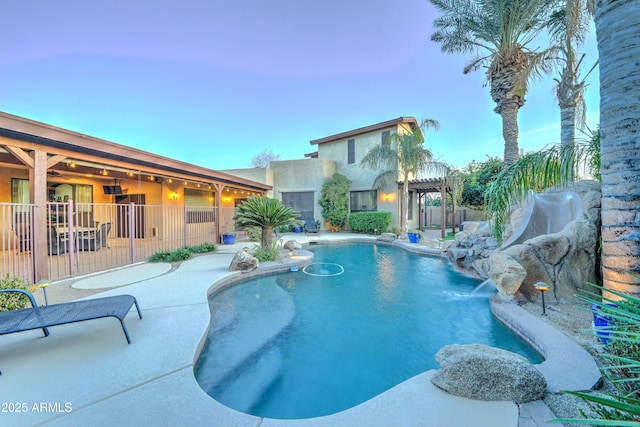 pool at dusk featuring a patio and pool water feature