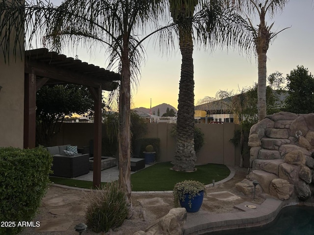 yard at dusk with an outdoor hangout area, a pergola, and a patio