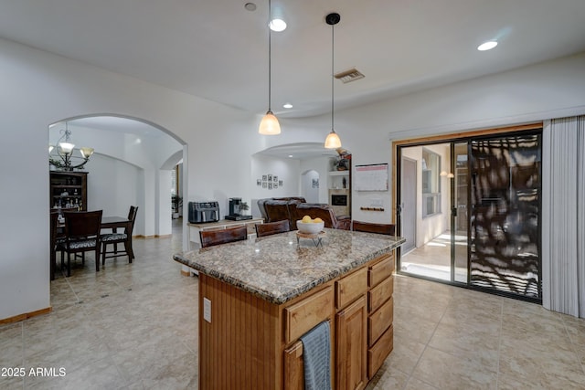 kitchen with pendant lighting, stone countertops, and a center island