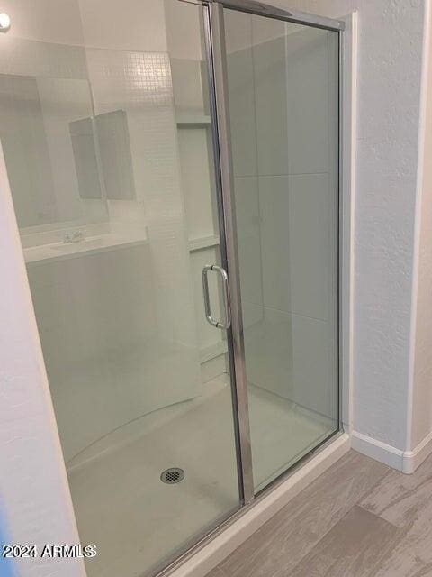 bathroom with a shower with shower door and hardwood / wood-style floors